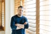Linear CEO Karri Saarinen stands with his arms crossed in front of a window with wooden blinds