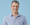 A headshot of Canva CTO Brendan Humphreys wearing a blue and white shirt.